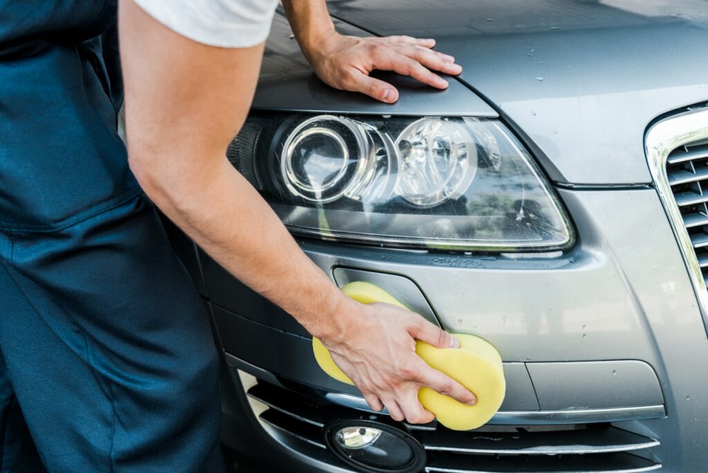 cropped view of man holding sponge while cleaning car